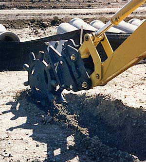 Compaction wheel compacting soil in trench after excavation. Five year guarantee on compaction wheels for skid steers, excavators, and backhoes.